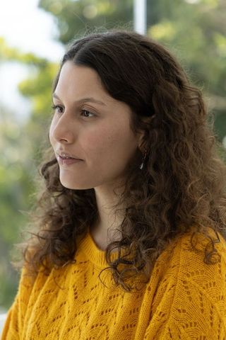 Young woman gazing left wearing mustard cable knit sweater natural window light portrait