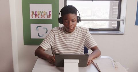 Boy engaging with tablet wearing headphones in classroom