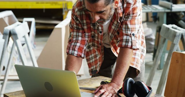 Carpenter Wearing Plaid Shirt Working on Laptop in Workshop - Download Free Stock Images Pikwizard.com