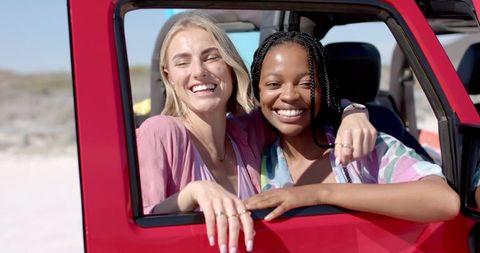 Diverse Friends Laughing Inside Car on Beach Road Trip