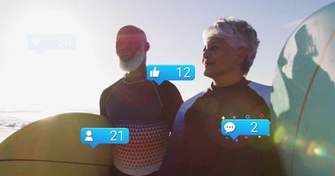 Older couple holding surfboards at sunny beach with social media icons