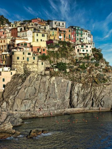Perching Mediterranean cliffside village with colorful houses above clear blue sea