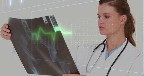 Female doctor analyzing x-ray with ecg overlay in lab