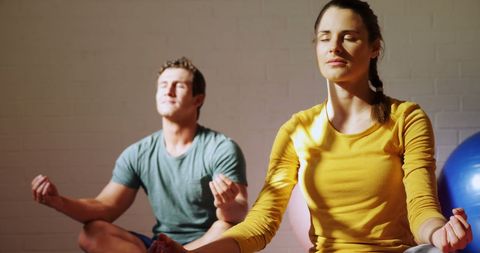 Focused Couple Practicing Yoga Meditation in Bright Gym Setting