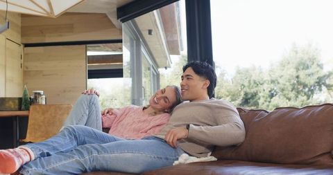 Couple Reclining on Leather Sofa in Sunlit Modern Living Room Wearing Cozy Knit Sweaters