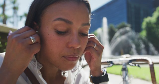 Young Woman Wearing Earphones Outdoors Near Fountain - Download Free Stock Images Pikwizard.com