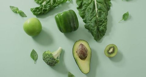 Assortment of fresh green vegetables and fruits on green background