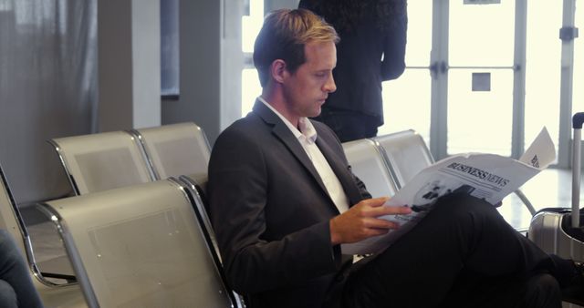 Businessman reading a newspaper in waiting area at airport terminal