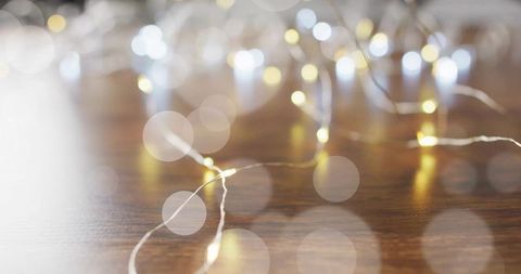 Fairy lights creating warm and cool bokeh on polished wood with copper wire