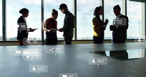 Five professionals engaged with devices in business meeting room