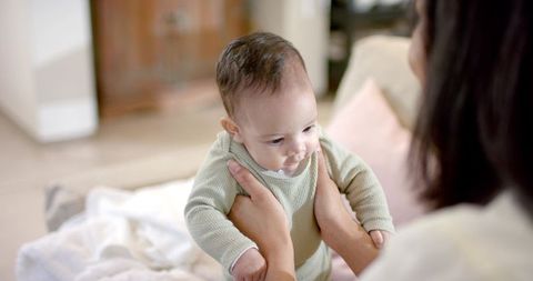 Mother holding baby on cozy blanket in living room