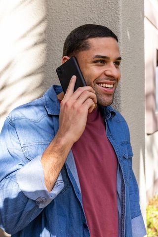 Young Hispanic Man in Denim Talking on Smartphone Outdoors