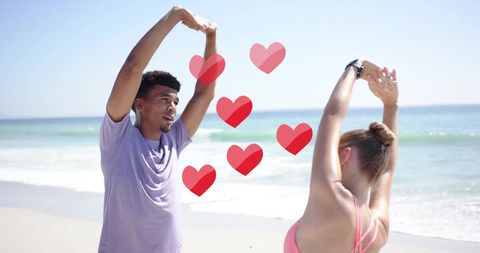 Diverse Couple Stretching on Beach with Hearts Overlay