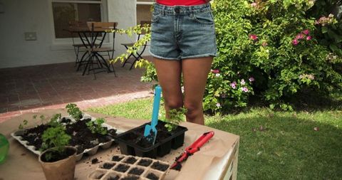Gardener preparing seedling trays on patio table in lush backyard