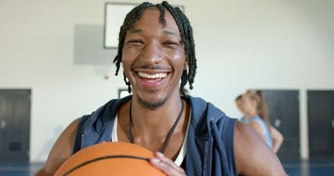 Joyful basketball player holding ball in gymnasium