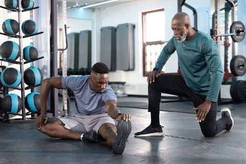 African american personal trainer coaching senior client stretching mobility & strength