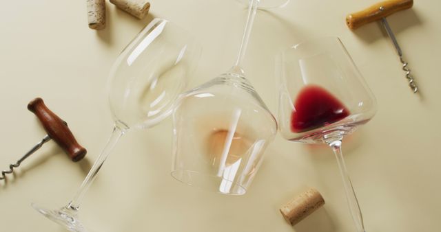 Wine glasses positioned on beige background, including S-curve filled with red wine, another white wine, a third containing rose wine, alongside scattered corks and corkscrews. Ideal for articles or advertisements related to wine tasting, entertaining, and hospitality industry content.