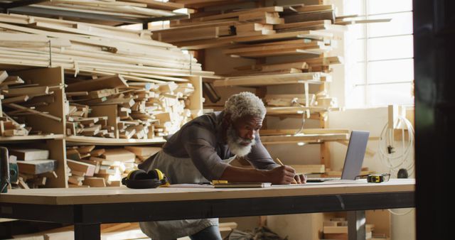 African american male carpenter sketching a project in a carpentry shop. carpentry, craftsmanship and handwork concept