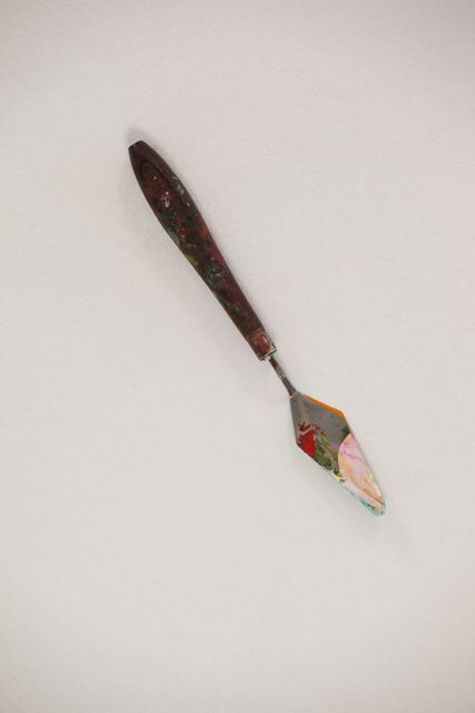 This image shows a close-up of a palette knife with paint smudges on its blade, set against a white background. Ideal for use in articles or advertisements related to art supplies, painting techniques, or creative tools. It can also be used in educational materials or blogs about art and painting.