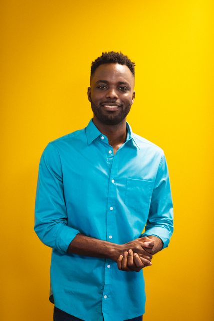 Portrait of smiling young african american businessman standing against yellow wall, copy space. unaltered, business, corporate business, occupation and office concept.