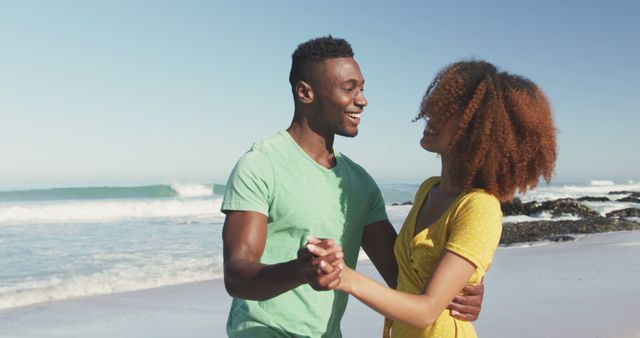 Happy biracial couple dancing on beach, hugging and smiling. Summer, relaxation, vacation, happy time, summer time, romance.