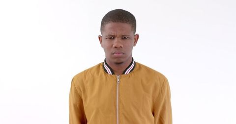 Serious young man wearing yellow jacket, expressing confidence
