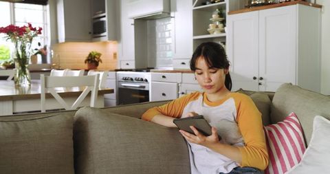 Young Woman Relaxing on Couch with Tablet in Modern Kitchen Living Room