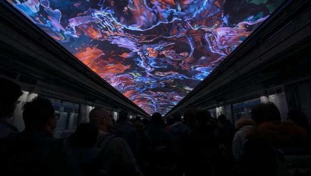 Commuters looking up at luminous abstract led ceiling in crowded subway tunnel