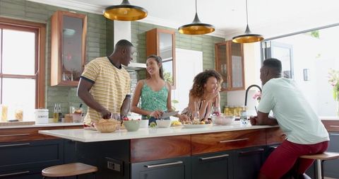 Group of friends enjoying cooking together in modern kitchen