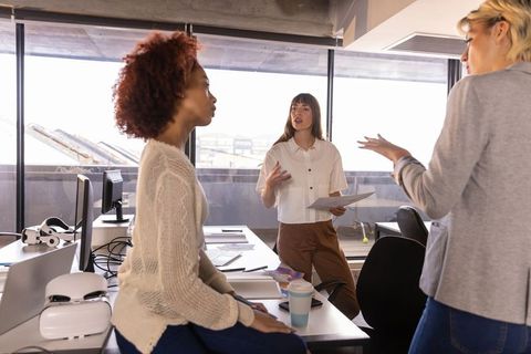 Diverse female colleagues discussing reports in modern urban office