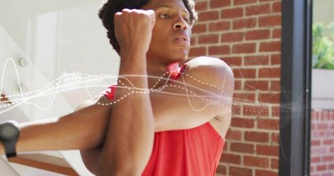 Focused athlete stretching arm across chest in gym with smartwatch and motion waveform