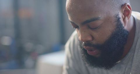 Bearded african man resting after intense workout, sweat-dusted face closeup