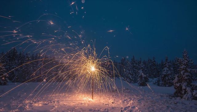 Golden fountain fireworks spraying sparks over snowy pine forest at night winter glow