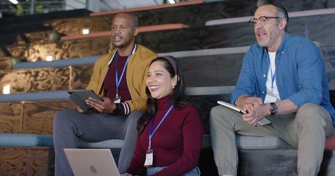 Smiling colleagues collaborating with laptop, tablet and notebook during workshop seminar