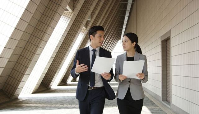 Walking business colleagues discussing documents in modern architectural corridor
