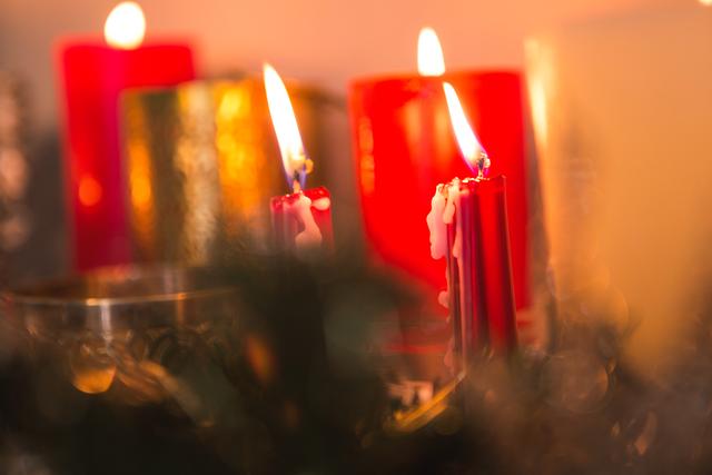 Close-up of burning candles creating a warm and cozy ambiance during Christmas time. Ideal for holiday greeting cards, festive decorations, seasonal advertisements, and creating a warm atmosphere in winter-themed projects.