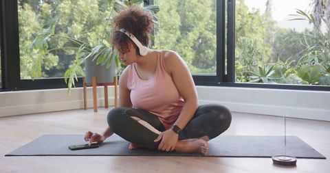 Woman in Yoga Pose Using Smartphone in Modern Home