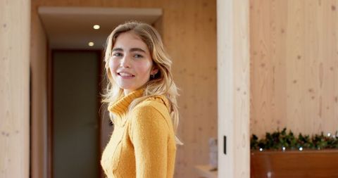 Smiling Woman in Mustard Sweater in Modern Wooden Home Interior