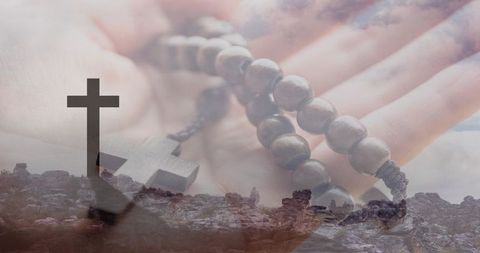 Hand holding wooden rosary beads over silhouetted cross on hilltop spiritual devotion