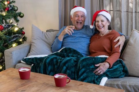 Senior couple sharing christmas moments with santa hats and hot beverages