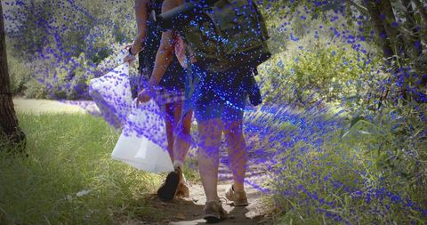 Two women walking forest trail carrying backpacks and shopping bag with blue speckle effect