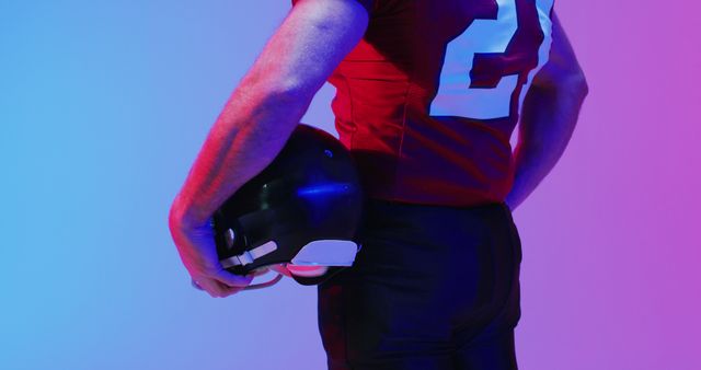 Image of midsection of caucasian american football player with helmet over neon purple background. American football, sports and competition concept.