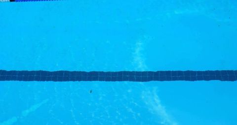 Sunlit swimming pool lane marker stretching across clear turquoise water with ripples