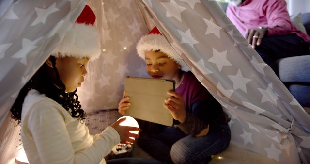 Children Wearing Santa Hats Playing with Tablet Inside Cozy Indoor Tent - Download Free Stock Images Pikwizard.com