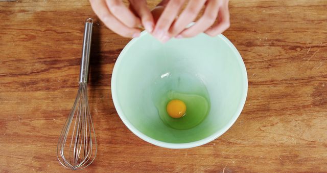 Person Cracking Egg into Mixing Bowl on Wooden Surface - Download Free Stock Images Pikwizard.com