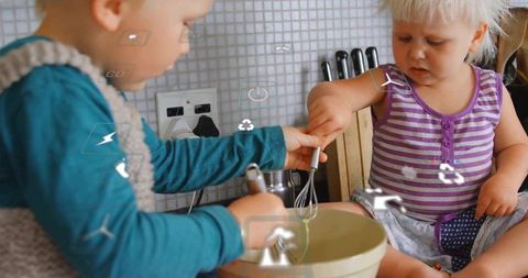 Siblings mixing batter in kitchen, playful cooking moment with whisks and laughter