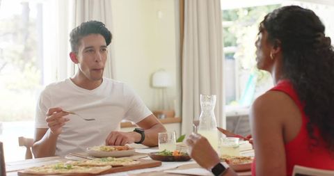 African american couple sharing pizza and sipping lemonade at sunlit wooden dining table