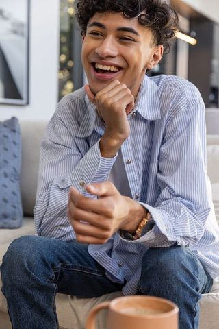 Young Man Relaxing with Coffee on Modern Sofa at Home