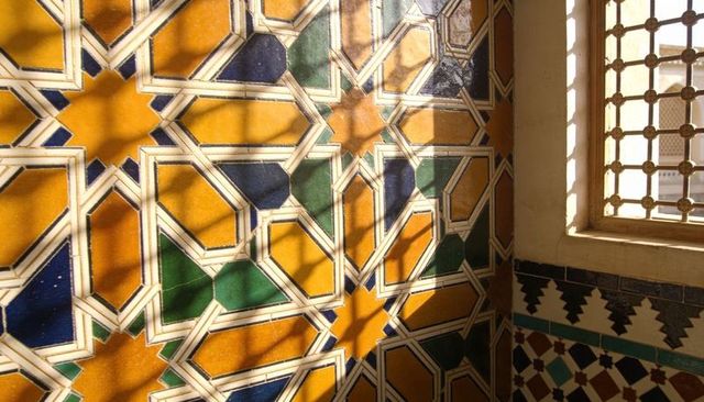 Sunlit moorish tiles showcasing geometric star patterns casting lattice window shadows