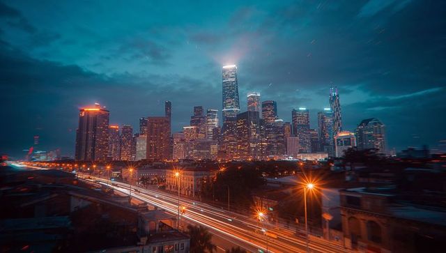 Illuminated Night Skyline with Skyscrapers and Highway Light Trails